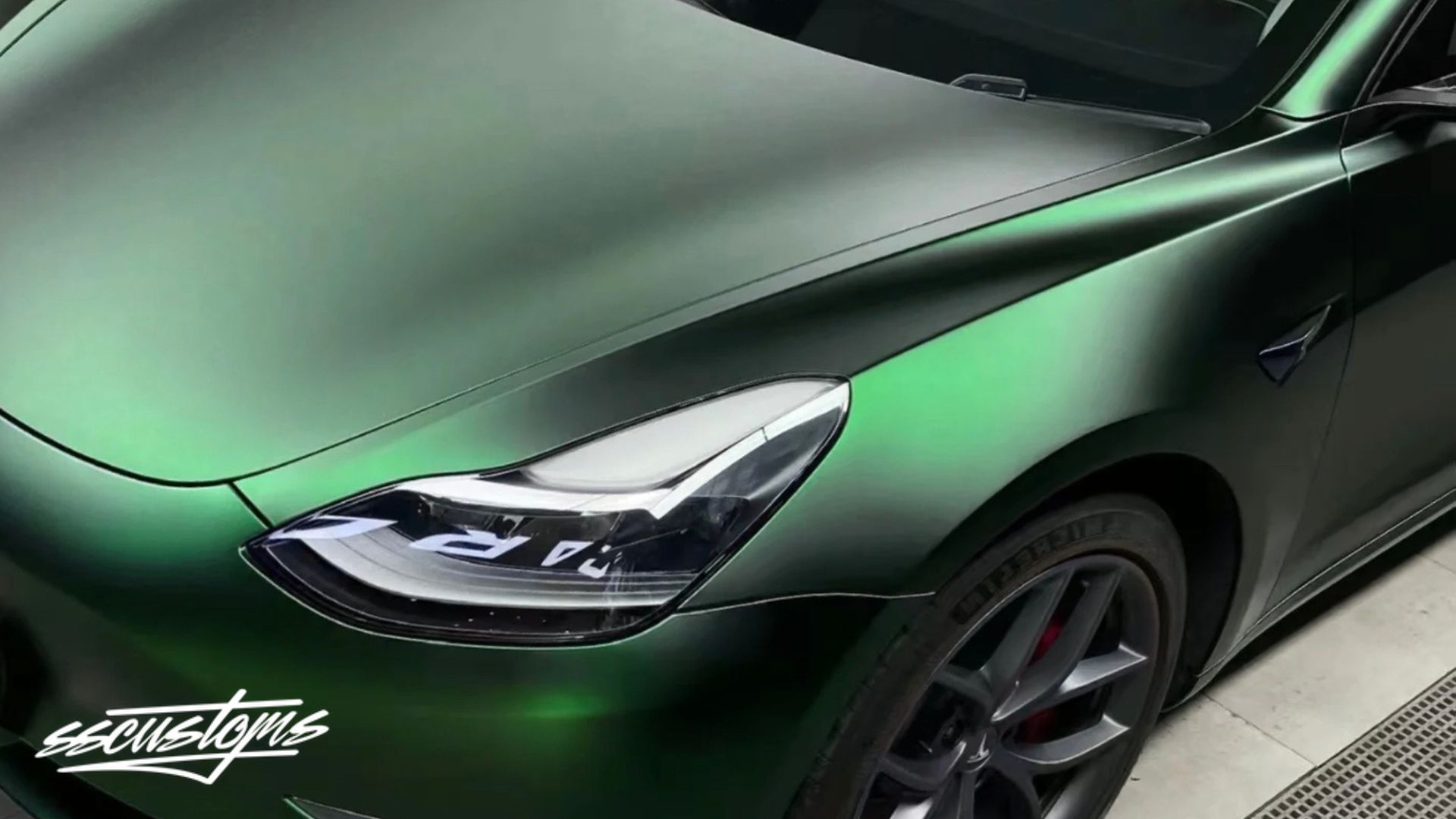 A green satin wrapped car shows a finished color change vinyl wrap across the hood front fender and side door. The text “ezcustoms” appears in the bottom left corner.
